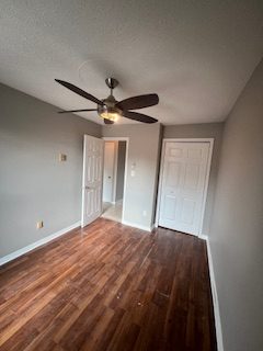 A bedroom with grey walls, a ceiling fan and white doors