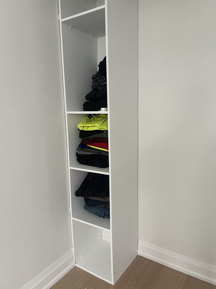 Tall painted white closet shelving with folded clothes