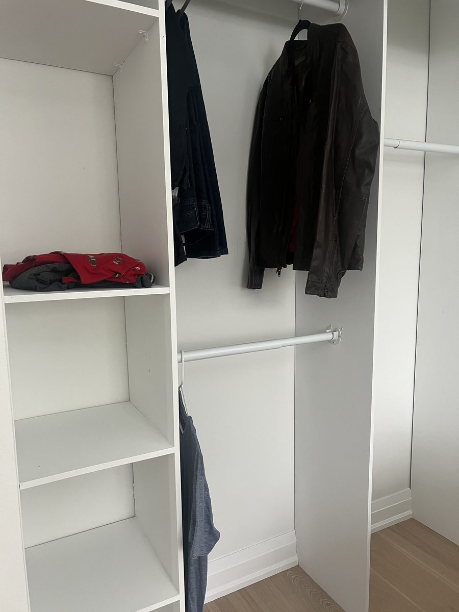 Painted white closet with a hanging rod and shelves