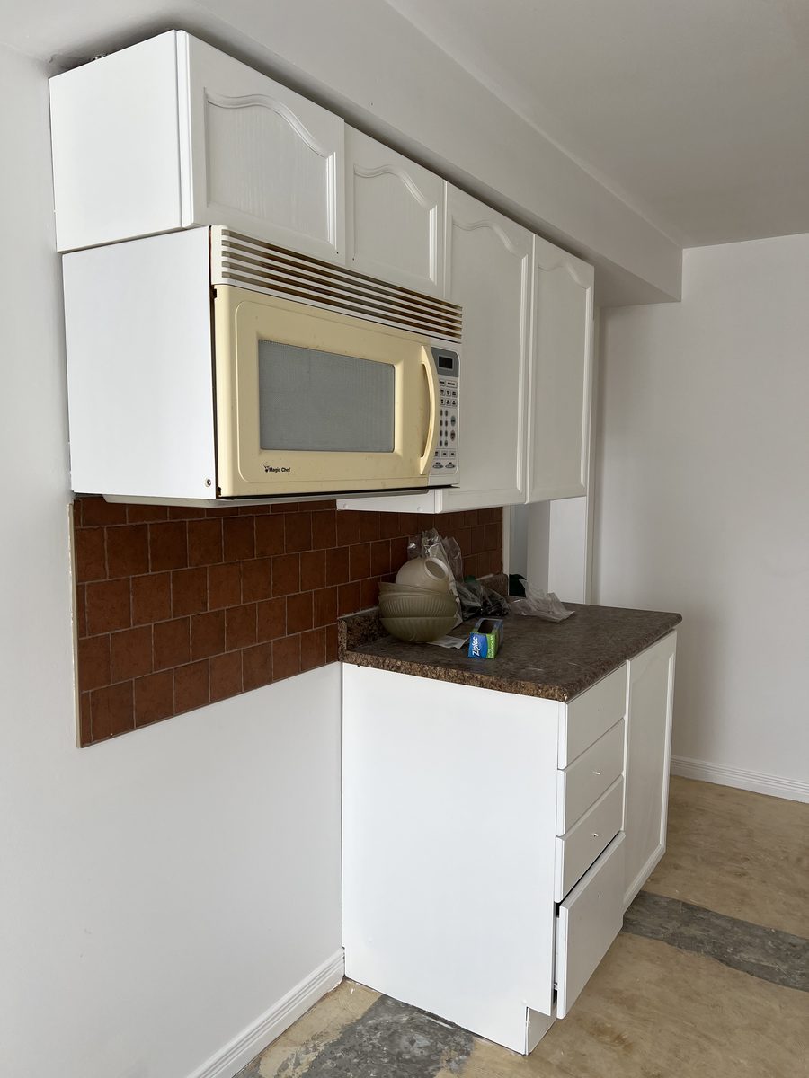 Painted white upper and lower cabinets beside the microwave
