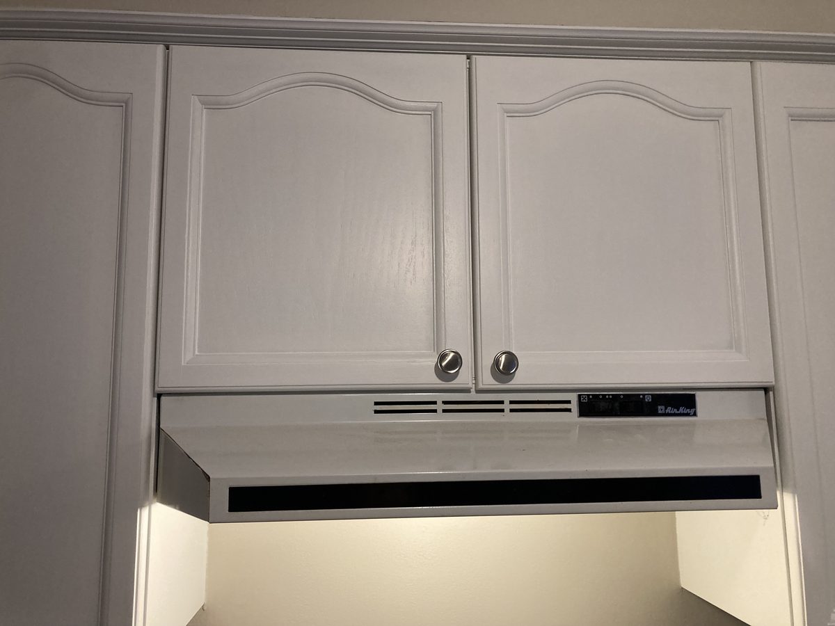 Painted white upper cabinets over the range hood